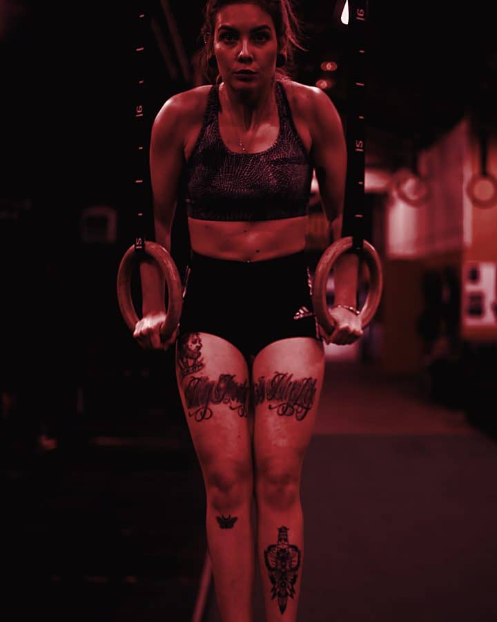 Athlete holding gymnastic rings in a dark gym