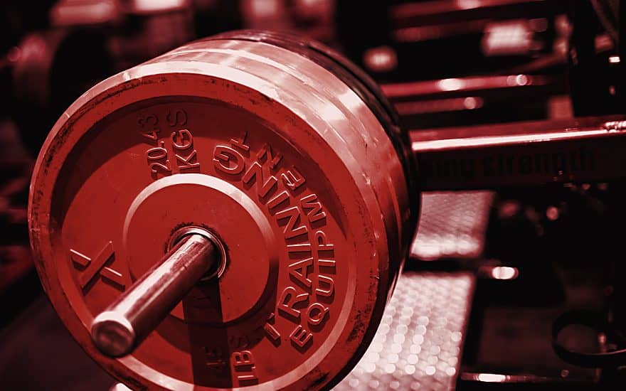 Close up of a loaded barbell plate in a dark gym
